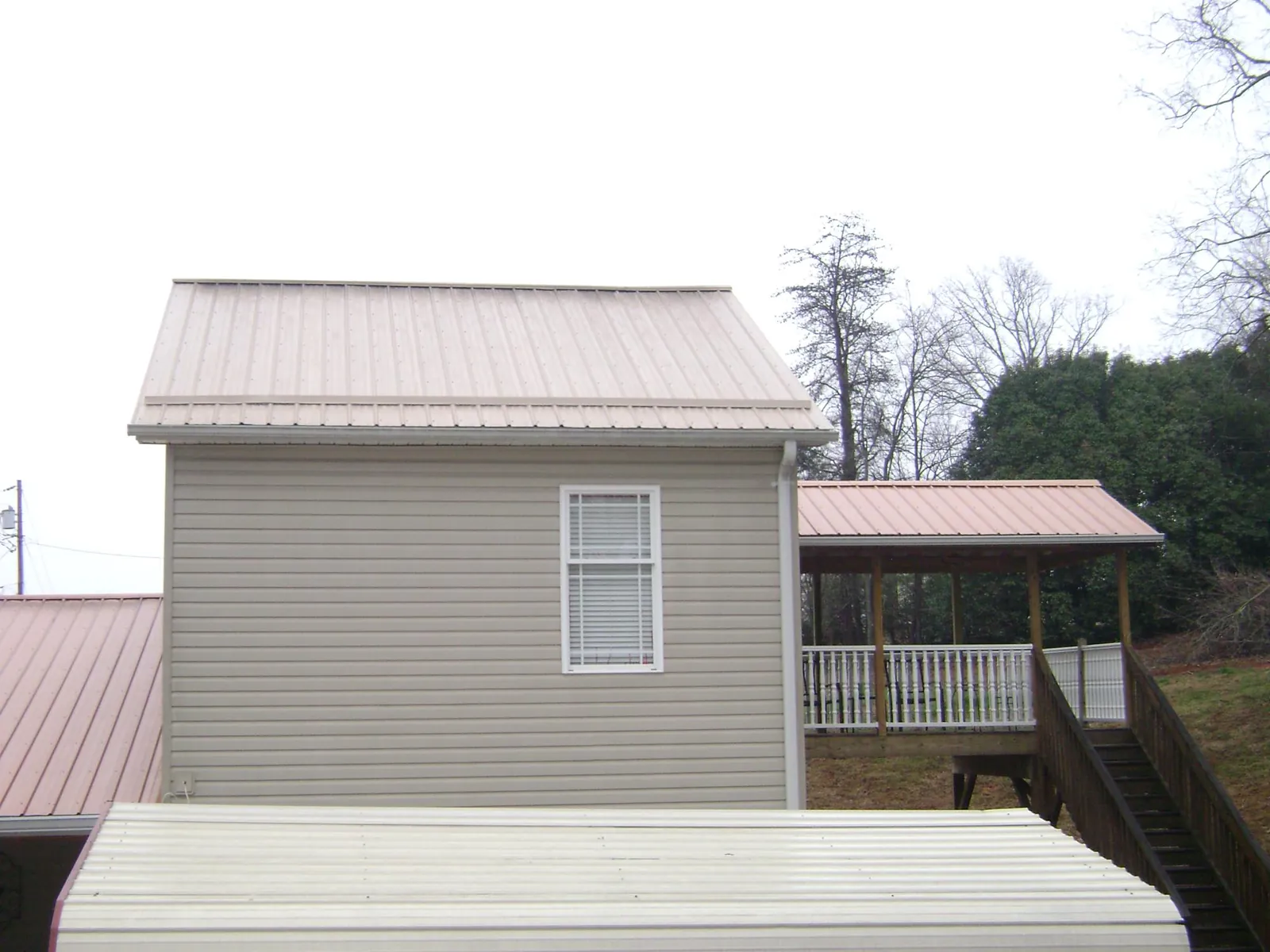 Tan metal roofs on a two story addition and attached porch, from a Roof Replacement job in Clarkdale